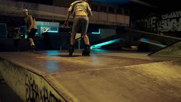 Active Hipsters Performing Jump Trick on Ramp at Night Skate Park with Graffiti alt