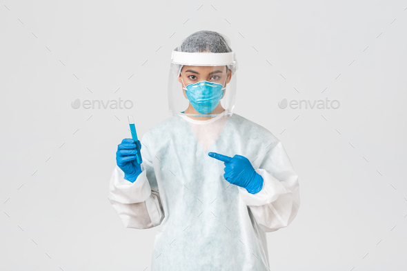 Covid-19, coronavirus disease, healthcare workers concept. Portrait of serious confident, asian female researcher, tech lab employee in personal protective equipment holding vaccine in test-tube.