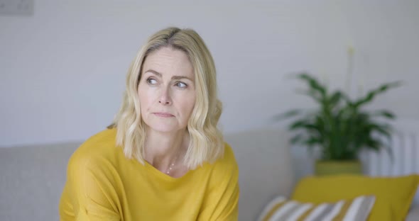 Worried woman sitting at home on sofa