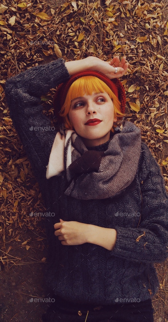 Young and redhead woman posing in an autumn scenery