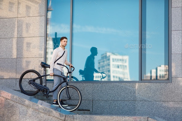 Short way to work. Young man walking down the stairs with bicycle