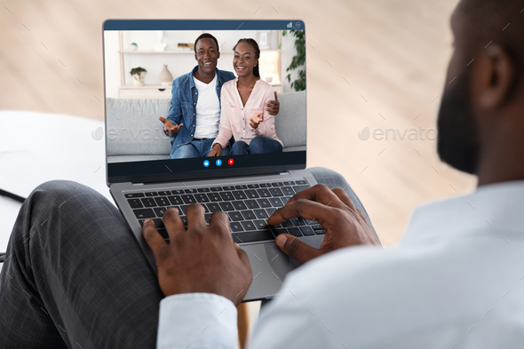 Marriage Therapy Online. Black counselor speaking with happy couple via video call on laptop computer, over shoulder view, selective focus