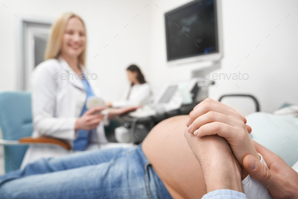 Husband holding woman\'s hand during ultrasound diagnosis