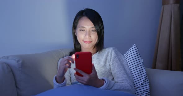 Woman look at mobile phone at home alt