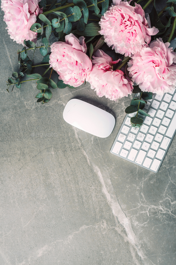 Feminine workspace. White computer keyboard, mouse, peony flowers, eucalyptus flowers on marble background. Top view. Copy space. Flat lay. Blogger, business concept. Mock up. Birthday, Woman day