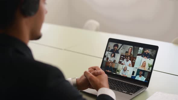Back View at Laptop Screen with Many Faces of Diverse People Involved in Group Video Conference