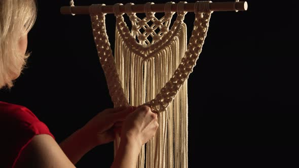 Women's Hands Weave a Macrame Pattern in Creative Workshop on Black Background alt