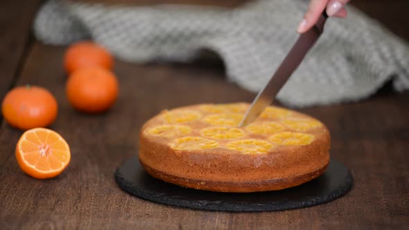 Female Hands Cuts Upside Down Tangerine Cake