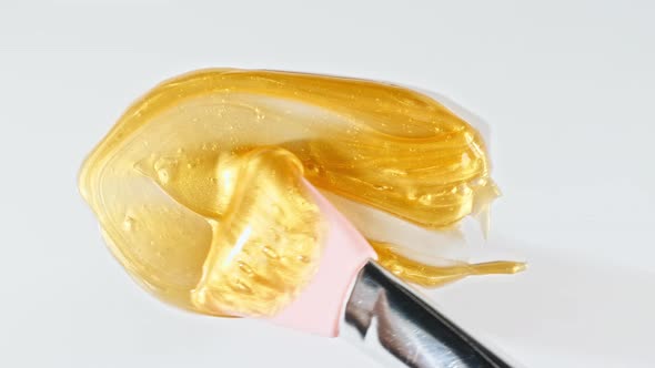 Artist Mixing Gold Paint Using Palette Knife Applied on a White Background alt