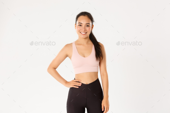 Sport, wellbeing and active lifestyle concept. Cheerful smiling asian girl promote you logo gym