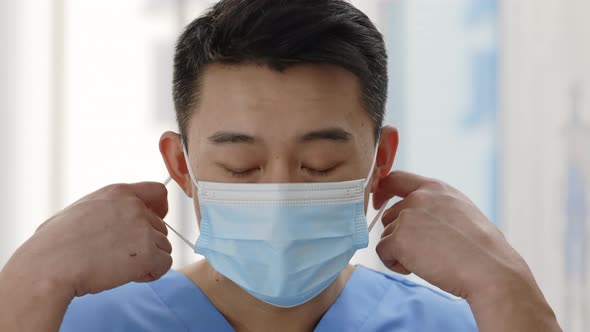 Close Up View of Asian Doctor Taking Off Medical Protective Mask Looking to Camera alt