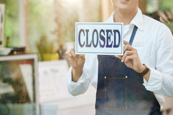 Cropped image of restaurant owner closing door and hanging sign