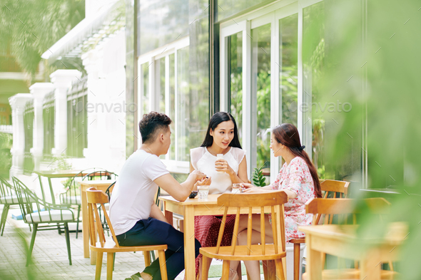 Group of friends having healthy breakfast in outdoor cafe