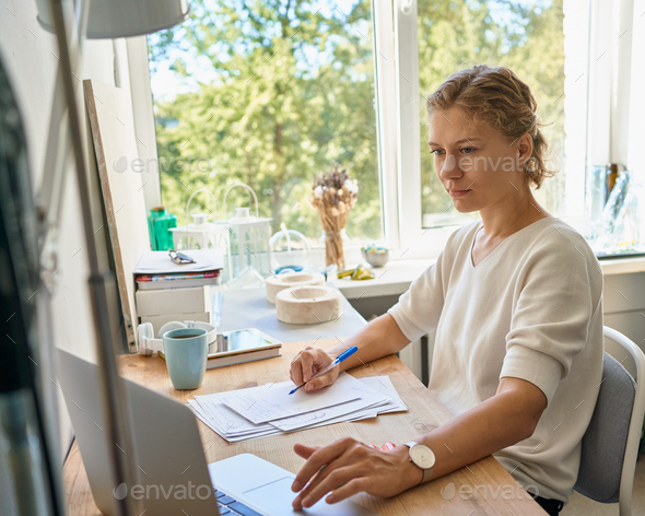 Young female entrepreneur designer writing on paper sheet, serious woman thinking and planning - Stock Photo - Images