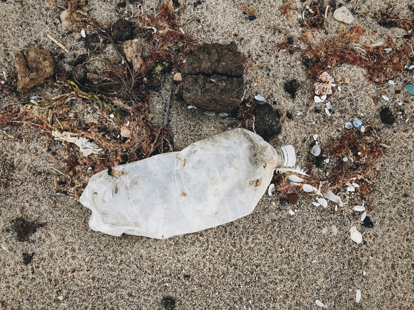 Single use plastic bottle in sand, marine trash on the beach