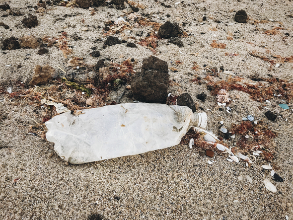 Single use plastic bottle in sand, marine trash on the beach