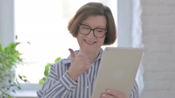 Portrait of Senior Woman Celebrating on Tablet in Office alt