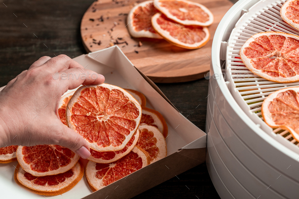 Close-up of unrecognizable woman packing dried grapefruit after dehydration into cartoon box