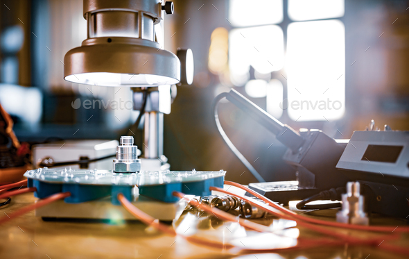Modern microscope, connectors component and large green microcircuit in workshop laboratory - Stock Photo - Images