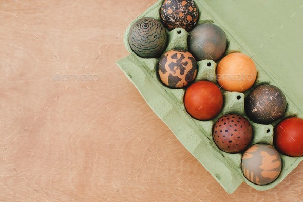 Stylish Easter eggs natural dye in carton tray on rustic table