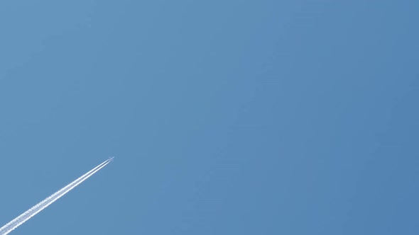 Passenger Airplane at Cruising Altitude with Contrail Against Blue Sky alt