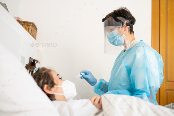 Doctor examining a little girl with a stethoscope at home - Stock Photo - Images