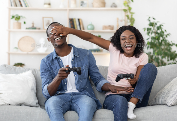 Happy boyfriend and girlfriend playing video games and holding