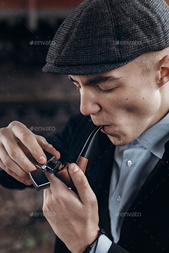 Man in retro outfit, smoking, lighting wooden pipe - Stock Photo - Images