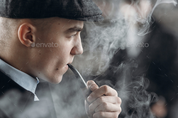 Stylish man in retro outfit, smoking wooden pipe - Stock Photo - Images