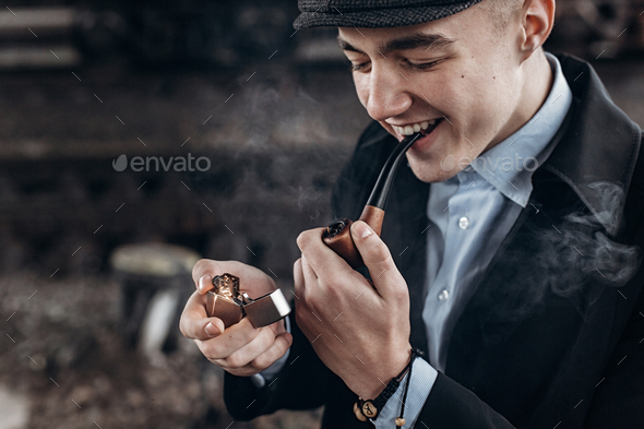 Man in retro outfit, smoking, lighting wooden pipe - Stock Photo - Images