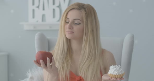 Young Blond Caucasian Woman Holding Apple and Cake. Portrait of Beautiful Lady Stretching Healthy alt