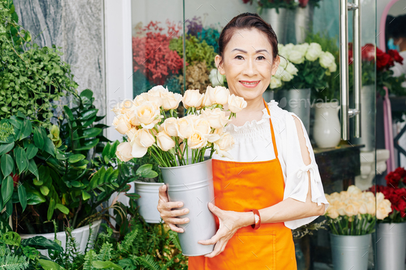 Senior florist with bucket of fresh roses