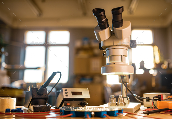 Modern microscope, connectors component and large green microcircuit in workshop laboratory - Stock Photo - Images