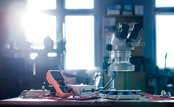 Modern microscope, connectors component and large green microcircuit in workshop laboratory - Stock Photo - Images