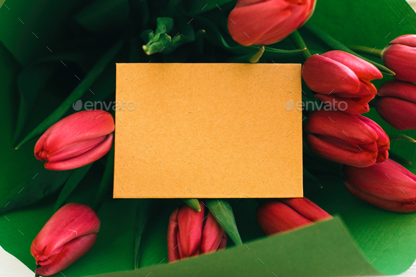 Beautiful red tulips bouquet in green paper and craft card with space for text - Stock Photo - Images