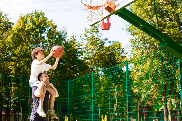 Man holding little boy on shoulders, playing basketball - Stock Photo - Images