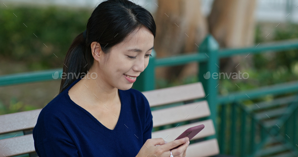 Young Woman work on smart phone and sit on the bench - Stock Photo - Images