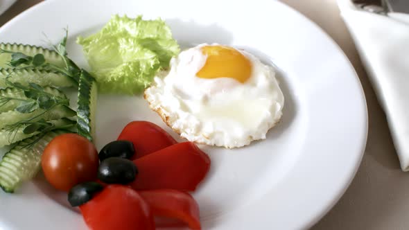 Fried Egg and Sliced Fresh Vegetables on Plate in Restaurant alt