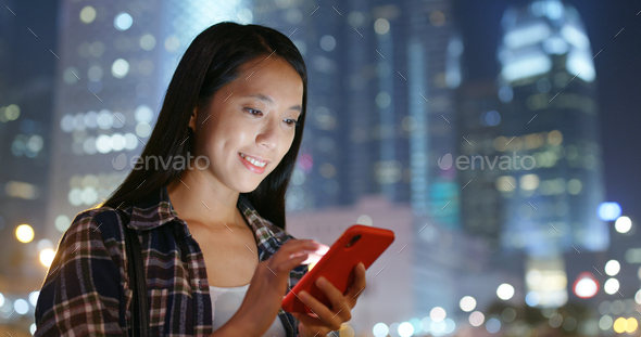Woman use of mobile phone in city at night - Stock Photo - Images
