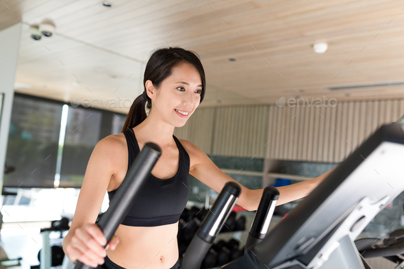 Sport Woman training on Elliptical machine in gym