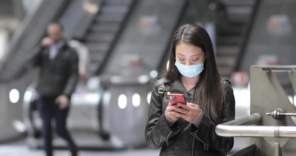 Chinese woman at train station in London wearing face mask alt