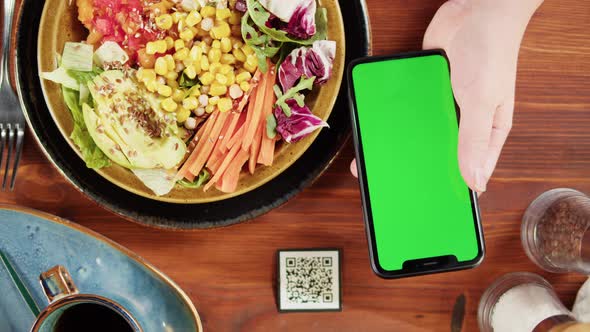 Eating Poke Bowl Salad Using Phone with Chroma Key Online Menu in Cafe or Restaurant alt