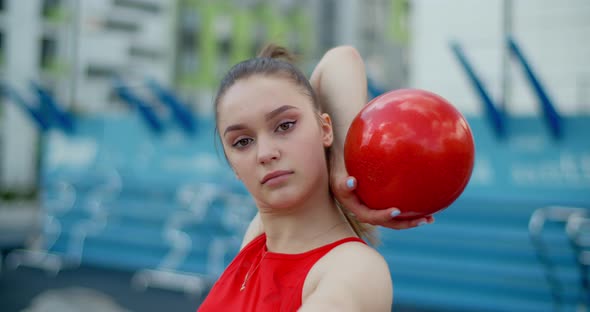 Portrait of Woman in Red Sports Costume Performing Callisthenics Exercises with Gymnastic Ball alt