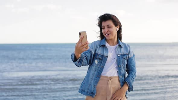 Woman at the Beach Uses Mobile Phone, Video Call. Video Conference with Mobile Phone, Speaking with