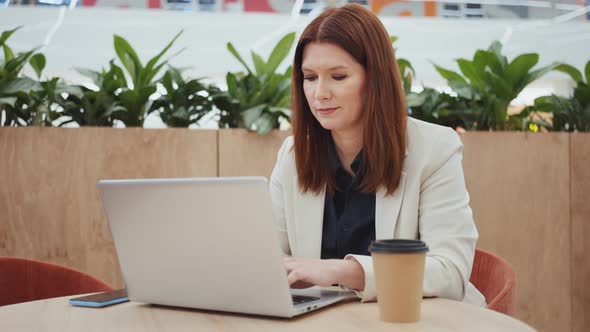 Freelancer Adult Woman Working on Laptop in Cafe alt