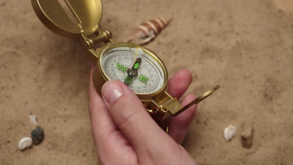 Man Hand Holding Gold Compass on Sand Background Closeup Golden Compass in Human Palm alt