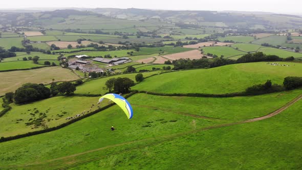 Parallax shot of a paraglider flying over the East Devon Countryside England alt