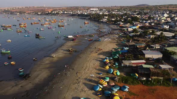 Busy morning of fishermen on Mui ne coast, unloading boats, loading trucks. Aerial alt