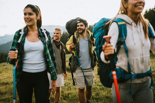 Group of friends trekking with backpacks walking outdoor