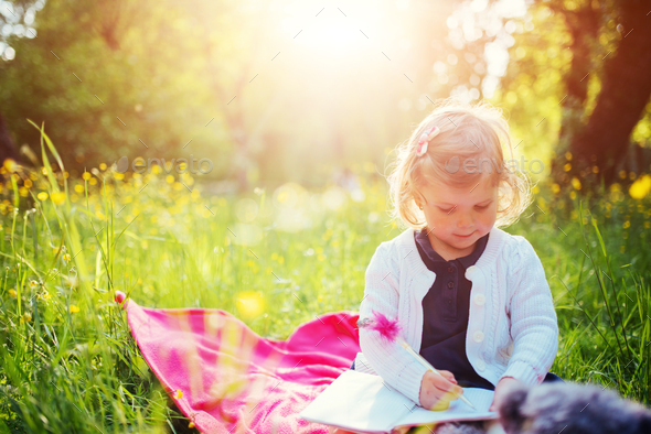 Happy little girl in a summer picnic at the park. - Stock Photo - Images